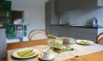 A cozy dining area in a modern kitchen. The table is set with plates and a decorative fruit basket.