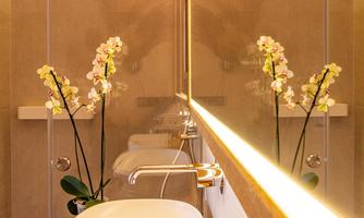 A modern bathroom with an elegant sink and a stylish shower. Flowers and soft lighting create a relaxing atmosphere.