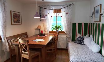 A cozy dining area with a wooden table and chairs. Plenty of light comes through the window, and the walls are cheerfully decorated.