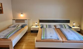 A comfortable room with two beds and an additional sleeping space. The walls are painted in neutral colors, and the furniture is modern and functional.