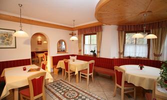 A cozy restaurant atmosphere with wooden details and warm colors. The tables are neatly set and the walls are decorated with pictures.