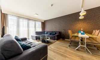 A modern living and dining room with a bright wooden floor. Comfortable sofas and an elegant dining table create an inviting atmosphere.