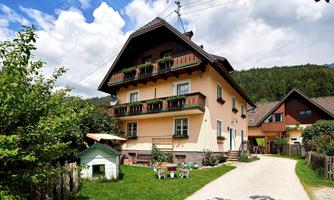A charming house in a quiet setting with a beautiful garden. The terrace is adorned with flowers and there are some outdoor seating areas.