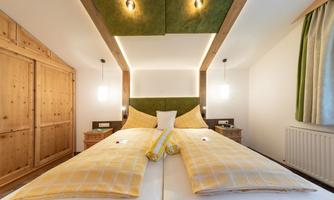 A modern bedroom with two single beds and a cozy decor. The walls are painted in neutral colors, with wooden furniture and soft lighting.
