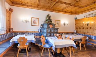 A cozy restaurant with wooden furniture and traditional decor. In the center stands a stylish stove, surrounded by set tables.