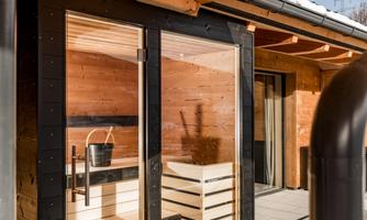 A modern wooden sauna with large glass windows. The interior is bright and inviting, perfect for relaxing.