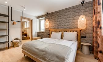 A modern bedroom with a double bed and stylish light sources. The walls are adorned with an appealing pattern, and the room has a bright, inviting atmosphere.