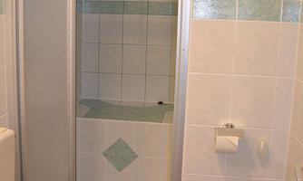 A modern bathroom with a shower and a toilet. The walls are brightly tiled, with a blue accent.