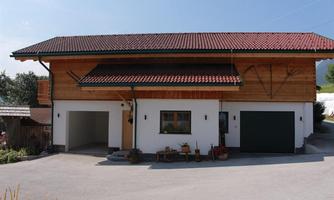 A modern house with wooden cladding and a red roof. The facade is friendly and inviting.