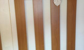 A wooden panel with several golden hooks. A heart pendant hangs from one of the hooks.