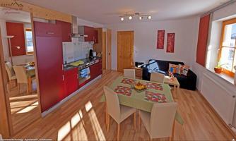 A modern kitchen with a dining area and a cozy living room.  
Bright wood floors and large windows create an inviting atmosphere.