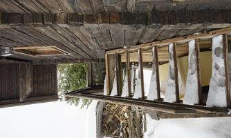 A wooden staircase leads to a winter house surrounded by snow. In the background, green trees are visible.