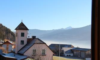 A picturesque village with a observation tower and many traditional houses. In the background, the mountains and a clear blue sky are visible.