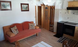 A cozy living space with a red sofa and a dining table. The kitchen is well-equipped and provides a warm atmosphere.