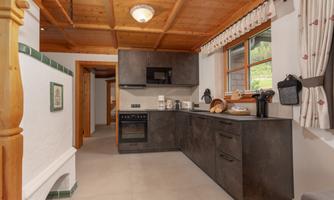 A modern kitchen with a wooden ceiling and elegant furniture. It is bright and well-equipped, ideal for preparing meals.