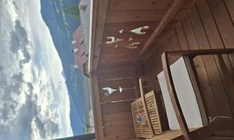 A cozy wooden balcony with two chairs and a view of the mountains. The atmosphere is relaxed and inviting.