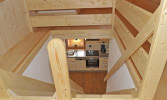 A bright wooden apartment with an open staircase. The kitchen is well-equipped and invites you to cook.