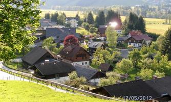 A picturesque village in the mountains with traditional houses and green meadows. Trees and blooming plants give the landscape an inviting atmosphere.