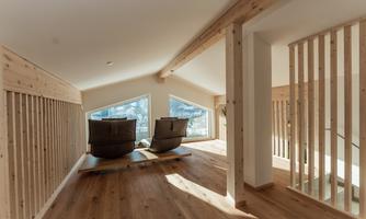 A bright interior with wooden walls and large windows. Two comfortable chairs are situated on a wooden platform.