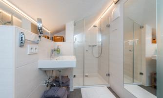 A modern bathroom with a glass shower and a white sink. Bright walls and elegant lighting create a pleasant atmosphere.