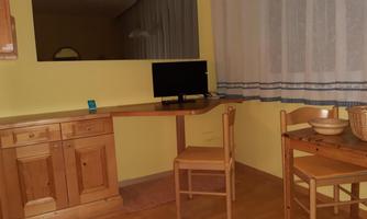 A simple room with a bright yellow paint. There is a desk, a computer, and a small table with chairs.