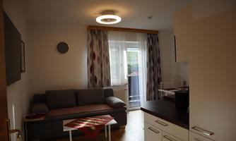 A cozy living space with a gray sofa and a table. Generous windows let in plenty of light.