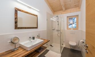 A modern bathroom with a spacious shower and an elegant sink. Bright colors and wooden details create an inviting atmosphere.