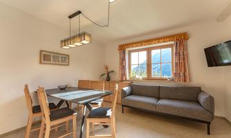 A cozy dining room with a wooden table and chairs. There is a beautiful view of the mountains from the window and plenty of daylight.