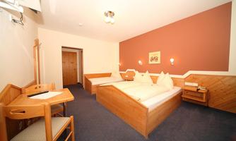 A cozy room with two beds and a wooden desk. The walls are painted in soft colors, and there is plenty of space.