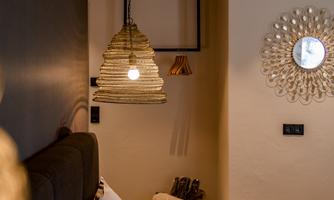 A cozy bedroom with a modern bed and stylish lamps. A round mirror hangs on the wall, reflecting the room's light.