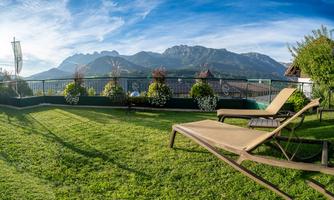 A relaxing lounger on a green meadow overlooking the mountains. The sky is clear and the surroundings are beautifully designed.