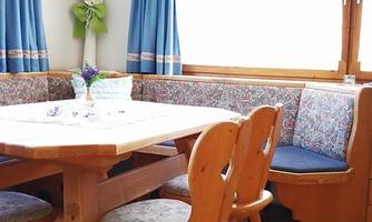 A cozy dining area with a wooden table and chairs. The blue curtains and bright lighting create an inviting atmosphere.