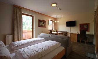 A modern room with two beds, a cozy sofa, and a table. Large windows offer a view of the surroundings and provide plenty of light.