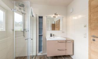 A modern bathroom with a glass cabin and a sink. The decor is designed to be bright and minimalist.