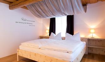 A stylish bedroom with a comfortable bed and wooden details. The gentle lighting and neutral colors create a cozy atmosphere.