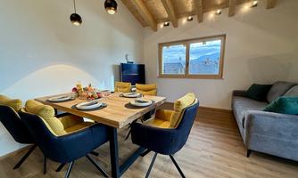 An inviting dining area with a wooden table and six modern chairs. Large windows let in plenty of daylight and offer a view of the surroundings.