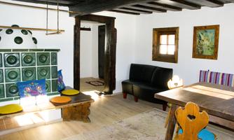 A cozy living space with an open fireplace and a black sofa. The room has light walls and an inviting atmosphere.