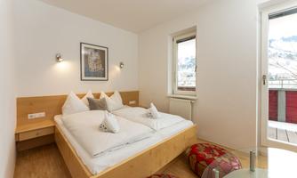 A modern bedroom with a large bed and cozy pillows. Large windows offer a view of the surroundings.