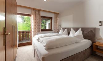 The Hochwurzen apartment has two separate bedrooms. This one additionally has direct access to the balcony. From there, you have a beautiful view of the surrounding mountains and the green nature.