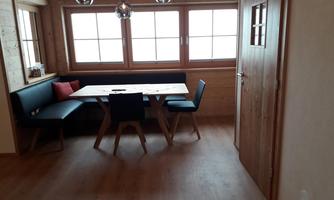 A cozy dining area with a wooden table and chairs. Large windows let in plenty of light and give the room an inviting atmosphere.