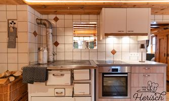 A modern kitchen with wood decor and white cabinets. It includes a stove, an oven, and a wood basket.