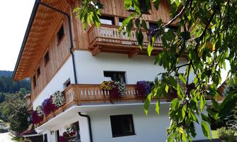A charming wooden house with balconies and colorful flowers. Surrounded by a picturesque landscape and trees.
