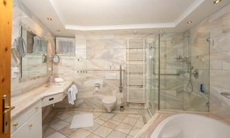 An elegant bathroom with modern fixtures and stylish marble. The amenities include a shower, a bathtub, and a towel warmer.