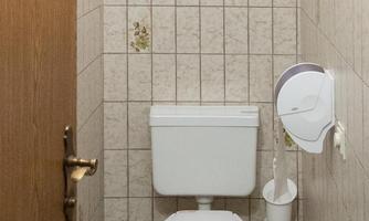 A simple bathroom with a toilet and tiled walls. The furnishings are functional and clear.