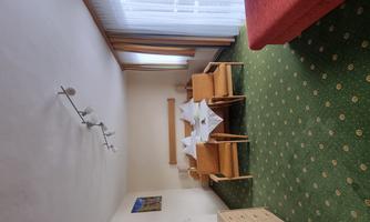 A bright room with a red sofa and a dining area. The carpet is green with dots and large windows provide plenty of daylight.