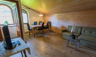 A bright room with wooden walls and a cozy sofa. A dining table with chairs is also available.
