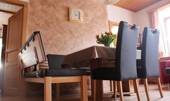 A cozy dining area with a wooden table and black chairs. A vase with fresh tulips is on the table.