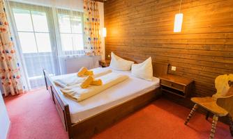 A cozy bedroom with wooden paneling and a large bed. The room is bright and friendly, with natural light and a harmonious decor.
