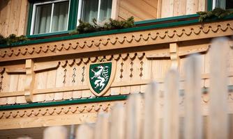 A traditional wooden house with a decorative crest on the facade. The architecture features alpine elements and an inviting atmosphere.