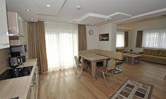 A modern apartment with an open living and kitchen area. Large windows provide plenty of natural light and an inviting atmosphere.